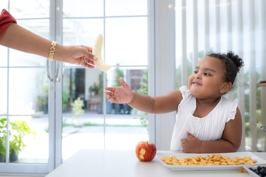 Mother peels bananas for her daughter to consume as a snack photo