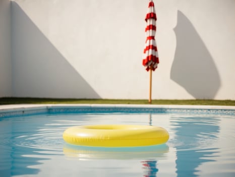 Bright Yellow Inflatable Ring in Clear Blue Swimming Pool with Striped Umbrella. photo