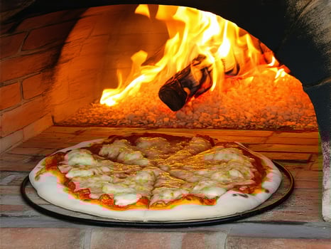 Freshly baked pizza cooking in a traditional wood-fired oven with a glowing flame photo