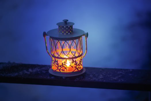 Decorative Christmas lantern with burning candle hanging on snow-covered fir- tree branch in a winter park. New year festive card, poster, postcard design. photo