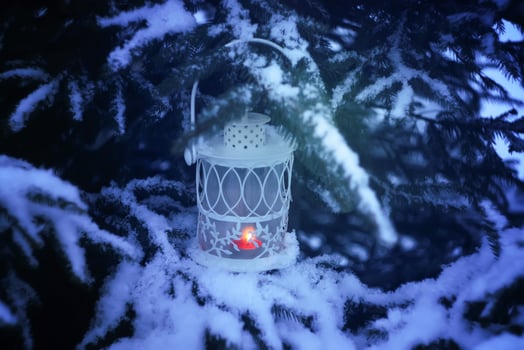 Decorative Christmas lantern with burning candle hanging on snow-covered fir- tree branch in a winter park. New year festive card, poster, postcard design. photo