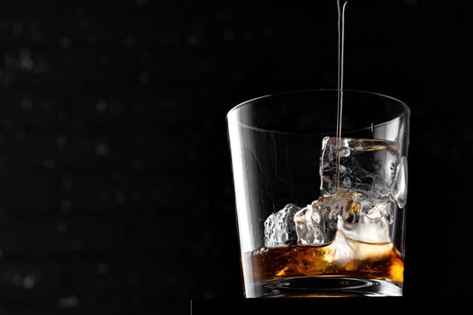 Whisky glass against dark black grunge wall photo