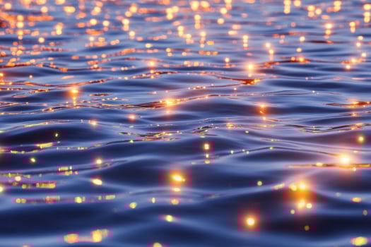 Floating red glowing plankton illuminate the deep ocean creating surreal reflections in tranquil waters photo