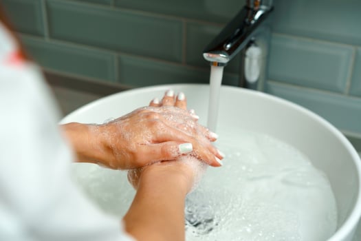 Close up of a woman washing her hands in a bathroom sink photo