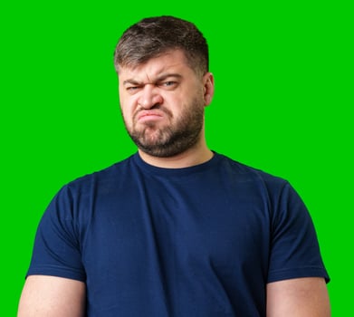 Man expressing confusion with crossed arms in front of a bright green background photo