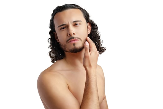 Young man with curly hair thoughtfully posing against a plain background photo