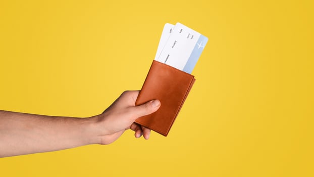 Travel restriction due to coronavirus. Man holding passport and plane tickets on blue background, closeup. Panorama photo