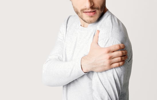 Healthcare and medicine. Man presses his hand to sore spot, isolated on gray background, studio shot photo