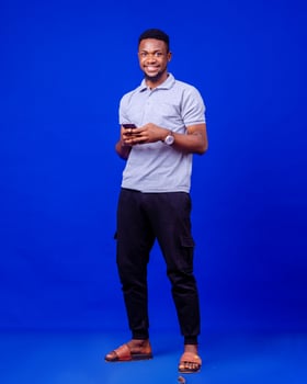 Cheerful millennial black man in casual using modern smartphone, checking social media, photo