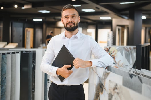 Portrait of a ceramic tile seller. The seller stands against the background of a large assortment of tiles photo