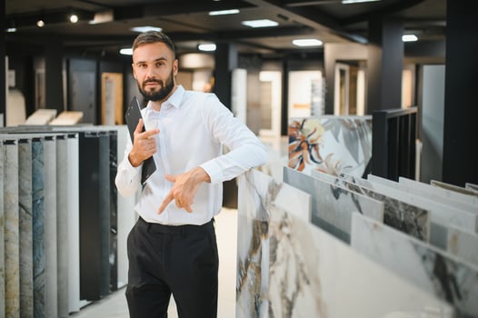 Portrait of a ceramic tile seller. The seller stands against the background of a large assortment of tiles photo