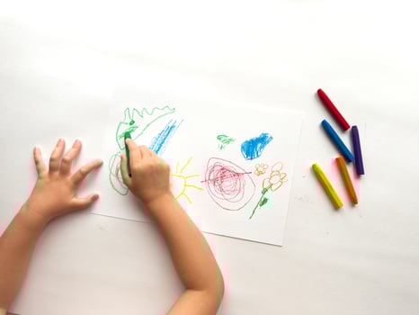 Child drawing colorful art with crayons on paper photo