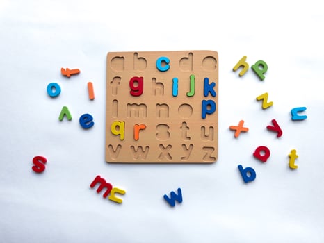Colorful alphabet puzzle with wooden board and loose letters on white background photo