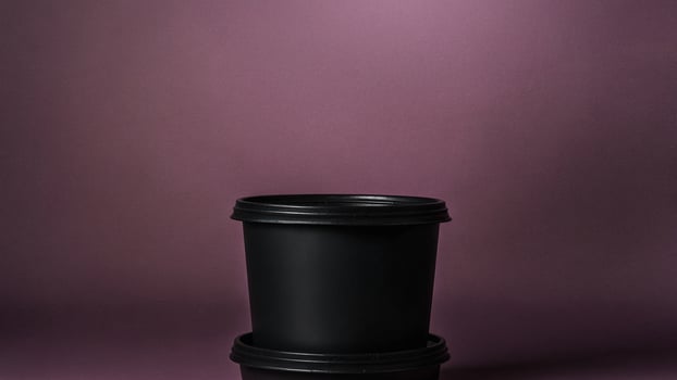 A black plastic container with a lid on a purple background photo