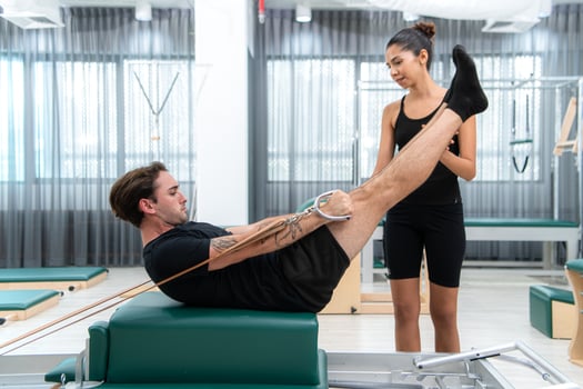 A young man and a young woman are doing pilates exercises on a pilates reformer photo