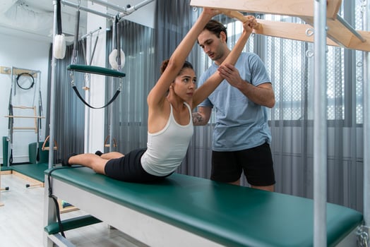 A young man and a young woman are doing pilates exercises on a pilates cadillac photo