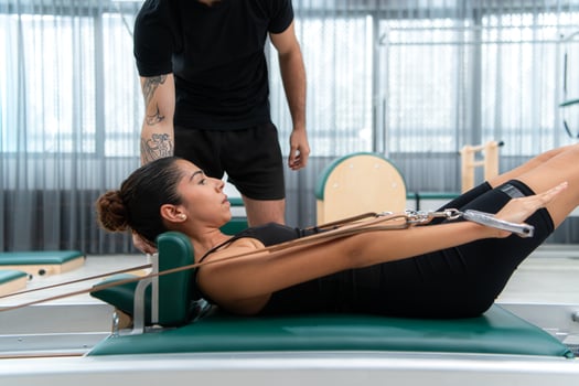 A young man and a young woman are doing pilates exercises on a pilates reformer photo