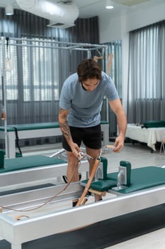 A young man doing pilates exercises on a pilates reformer photo