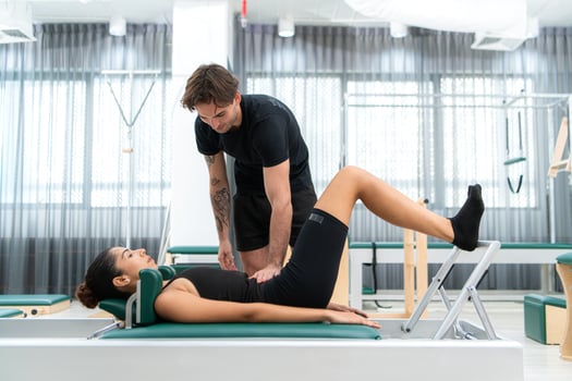 A young man and a young woman are doing pilates exercises on a pilates reformer photo