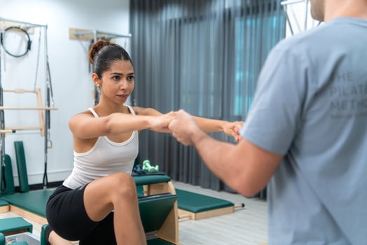 A young man and a young woman are doing pilates exercises on a pilates reformer photo