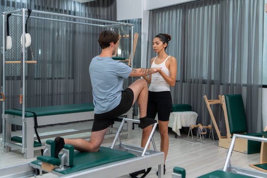 A young man and a young woman are doing pilates exercises on a pilates reformer photo