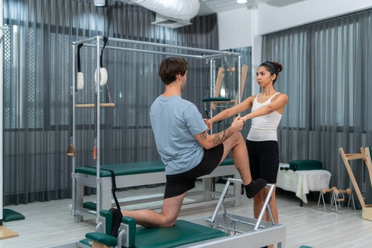 A young man and a young woman are doing pilates exercises on a pilates reformer photo
