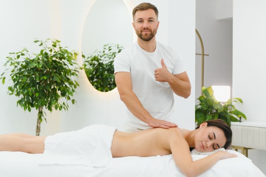 Osteopath massaging back of woman lying on front in health spa photo