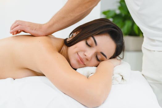 A young brunette woman receives a professional back massage in a spa salon. A beautiful naked lady in a towel with perfect skin gets a relaxing massage. The concept of luxury professional massage photo