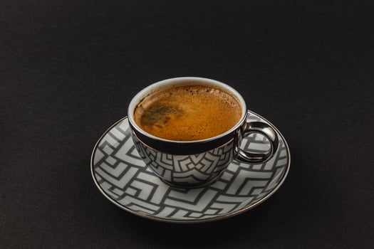 Fresh strong espresso in a silver cup on a plate on a black background photo