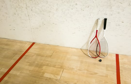 Two rackets and two squash balls lie on the parquet floor. photo