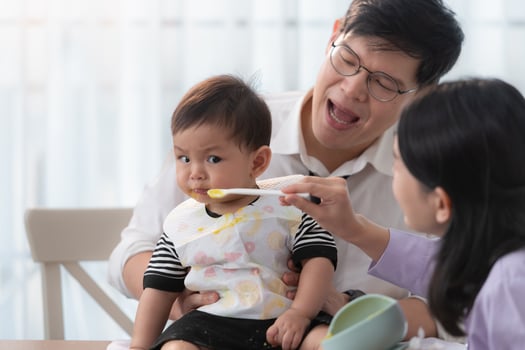 Father and mother feed their son breakfast before going to work in the kitchen of the house photo