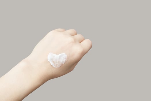 Caucasian female hand with heart shaped cream on neutral background for skincare concept. photo
