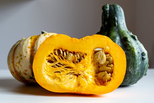 Cut and two whole pumpkins on a dark background on a white table photo