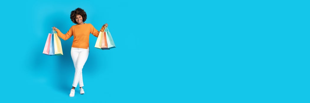 Joyful shopper holds colorful shopping bags, celebrating a successful trip in search of discounts. The bright blue background emphasizes the festive mood of the shopping occasion. photo