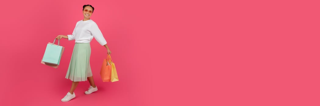 Big Sales. Excited Happy Asian Woman Holding Bright Shopping Bags In Hands While Walking Over Pink Studio Background, Cheerful Shopaholic Lady Enjoying Seasonal Discounts, Copy Space photo