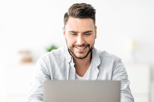 Home office concept. Closeup portrait of happy guy working on pc laptop, sitting at workplace at home interior. Excited male student using computer, study and education photo