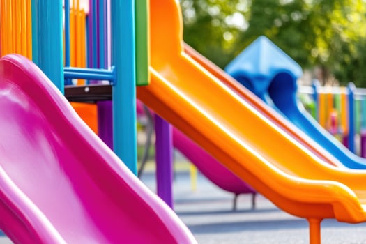 Colorful playground featuring orange slides, pink swings, and green climbing frames in a sunny park setting designed for childrens play and enjoyment photo