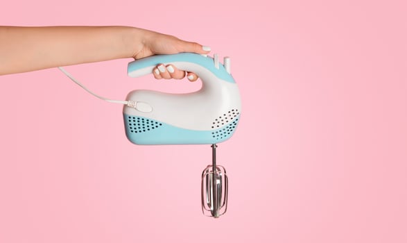 Millennial girl holding electric mixer on pink background, close up. Empty space. Panorama photo
