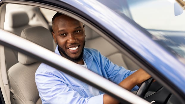 Positive young African American guy driving car and looking through open automobile door, parking or searching for fellow traveler passenger. Auto test drive, leasing, buying, rental concept photo
