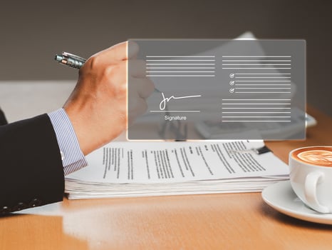 A businessman uses a pen to sign electronic documents on a virtual screen while sitting in the office photo