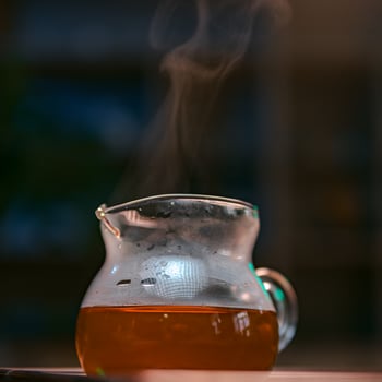 A beautiful glass pitcher filled with steaming herbal tea, exuding inviting aromas and warmth photo