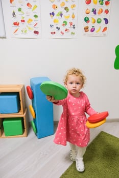 Beautiful blonde baby girl playing in kindergarten photo