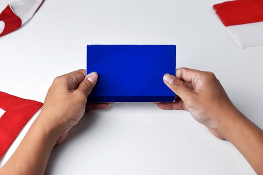 A person holds and shows a blue savings account book with white background photo
