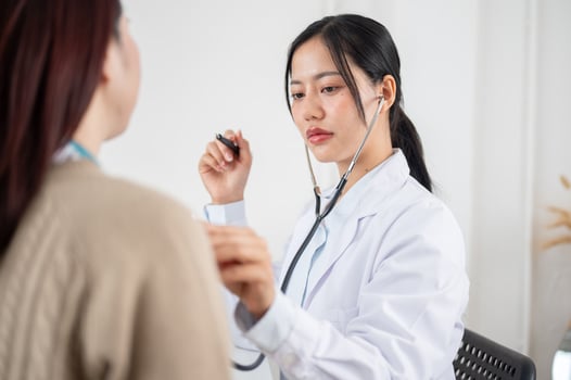 A doctor using a stethoscope to listen to a patient's lung and heartbeat sounds. photo