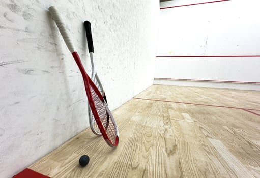 Two rackets and two squash balls lie on the parquet floor. photo
