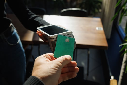 A man accepts payment from a customer through a credit card terminal in a store or cafe photo