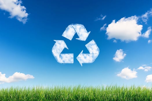 Recycle symbol on grass with blue sky and clouds photo