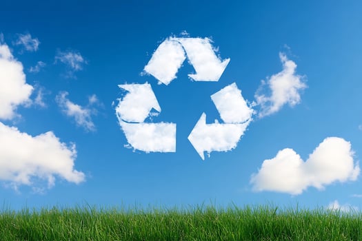 Recycling symbol on grass with blue sky and clouds photo