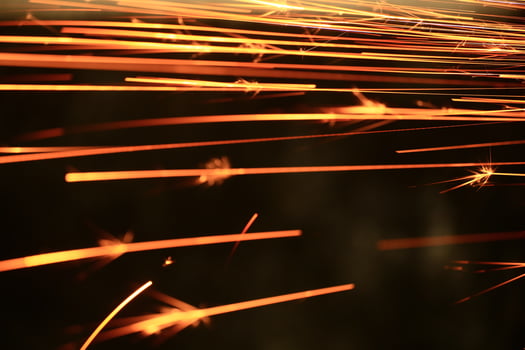 Spraying sparks from metalworking on a dark background photo