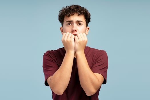 Scared shocked boy, pupil wearing red t shirt looking at camera standing isolated on blue background photo